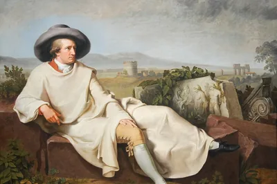 Ein Mann mit breitem Hut und hellem Mantel liegt auf Steinblöcken vor antiken Ruinen, Goethe in der roemischen Campagna, Tischbein, 1787.